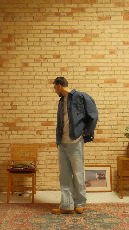 Person standing in a room with wooden floors and furniture.